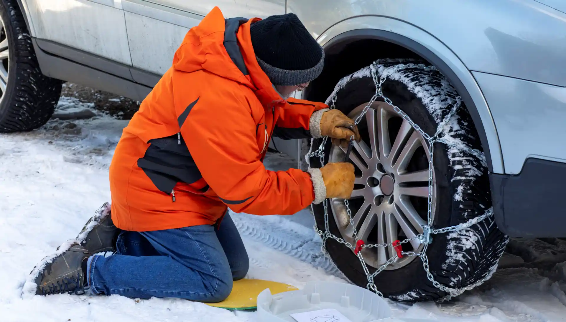 homme en train de mettre des chaines neige sur sa voiture