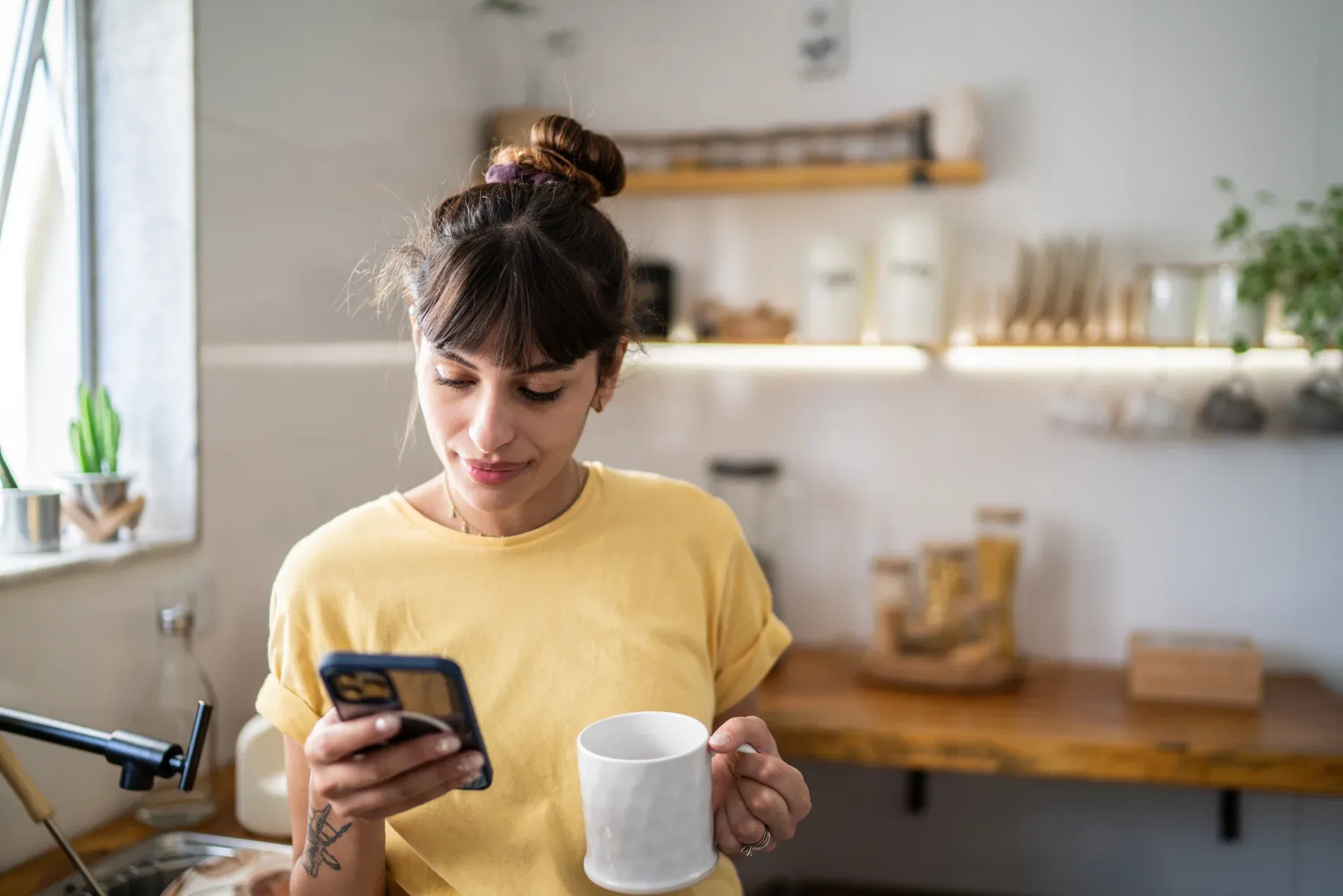 femme regardant son téléphone avec café à la main